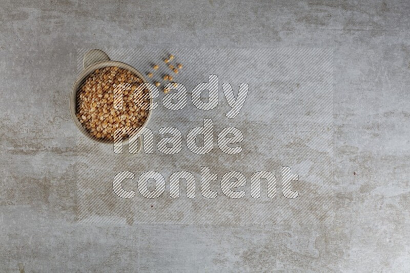 corn kernel in a off-white handheld ceramic bowl on a grey textured countertop