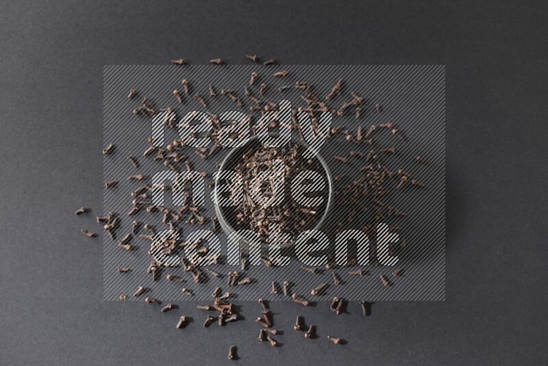 وعاء فخاري أسود ممتلئ بحبوب القرنفل علي خلفية سوداء