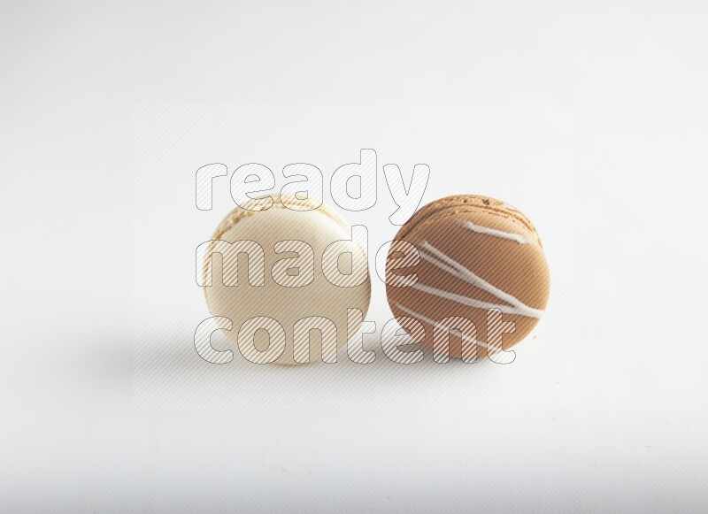 45º Shot of of two assorted Brown Irish Cream, and White Caramel fleur de sel macarons on white background