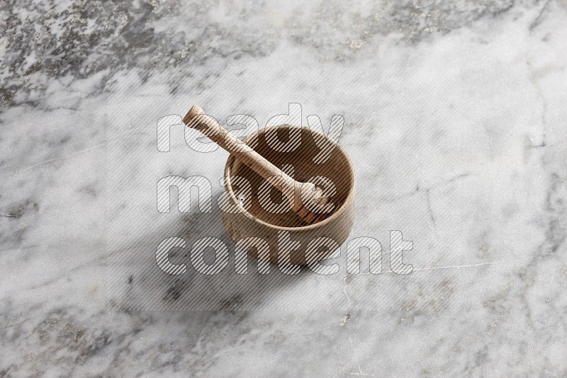 Multicolored Pottery bowl with wooden honey handle in it, on grey marble flooring, 65 degree angle