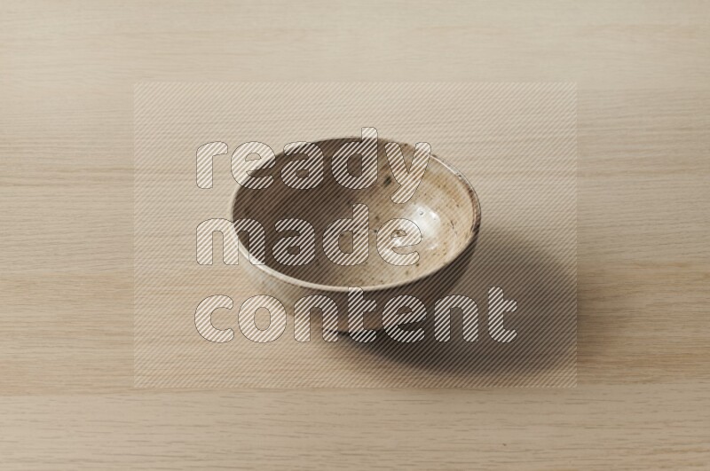 A beige pottery bowl on light wooden background