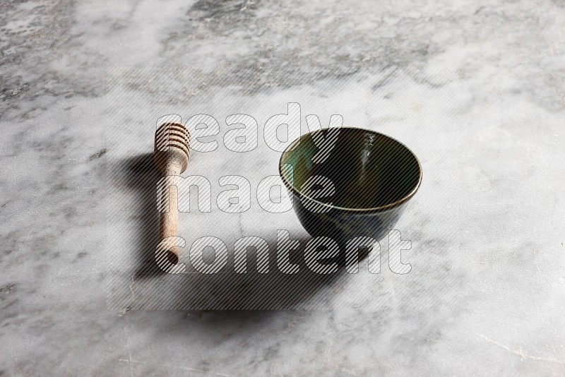 Decorative Pottery bowl with wooden honey handle on the side with grey marble flooring, 45 degree angle