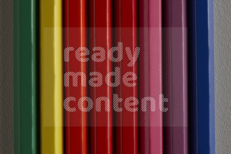 مجموعة من أقلام الرصاص الملونة مرتبة لتعرض تدرجا من الألوان المختلفة علي خلفية رمادية