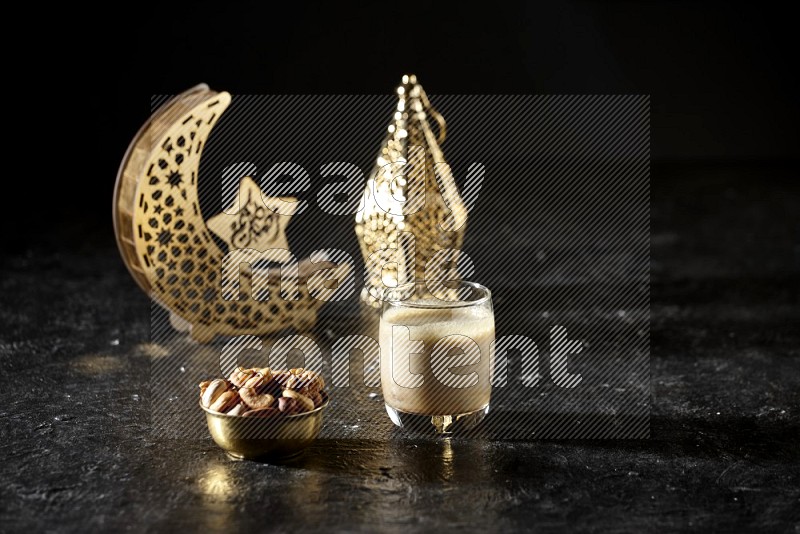 Nuts in a metal bowl with Nuts smoothie beside golden lanterns in a dark setup