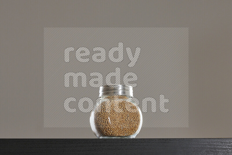 Mustard seeds in a glass jar on black background