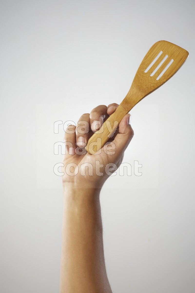 Male Hand Holding Slotted Turner on white background