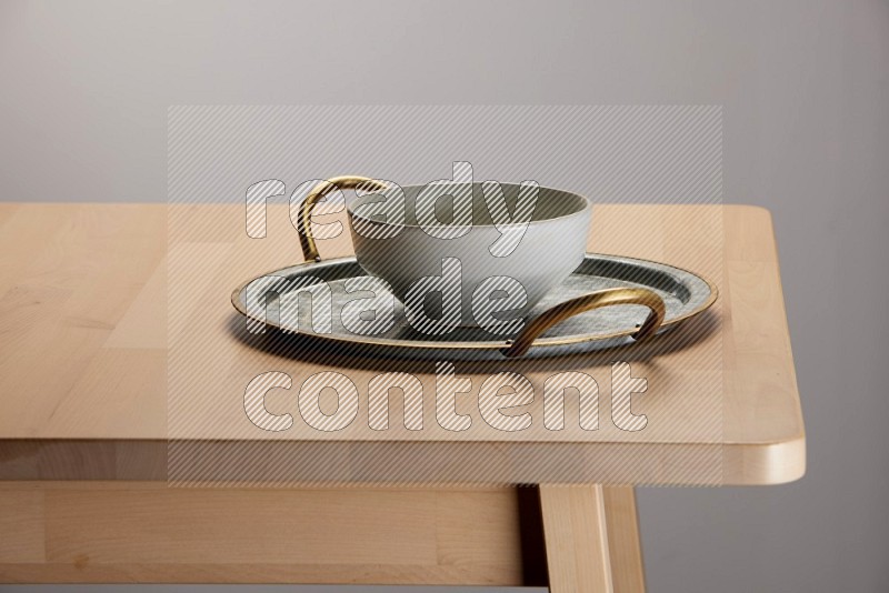 grey bowl placed on a rounded stainless steel tray with golden handels on the edge of wooden table