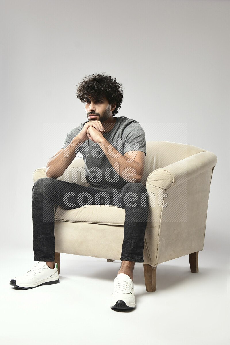 رجل يرتدي ملابس كاجوال يجلس علي كرسي و يقوم بإشارات باليد علي خلفية بيضاء