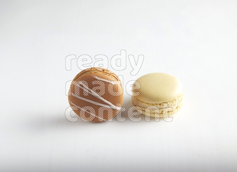 45º Shot of of two assorted Brown Irish Cream, and Yellow Vanilla macarons on white background