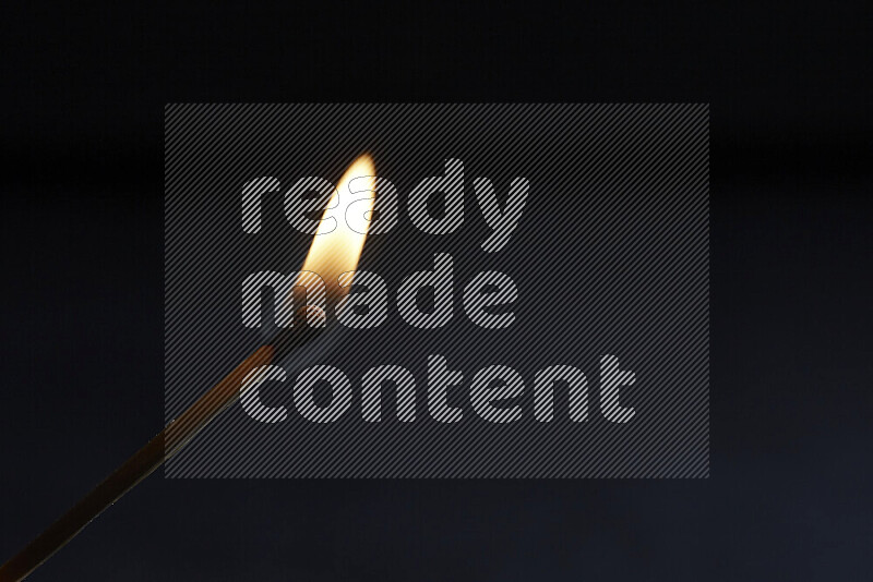 A burning matchstick isolated on dark backdrop