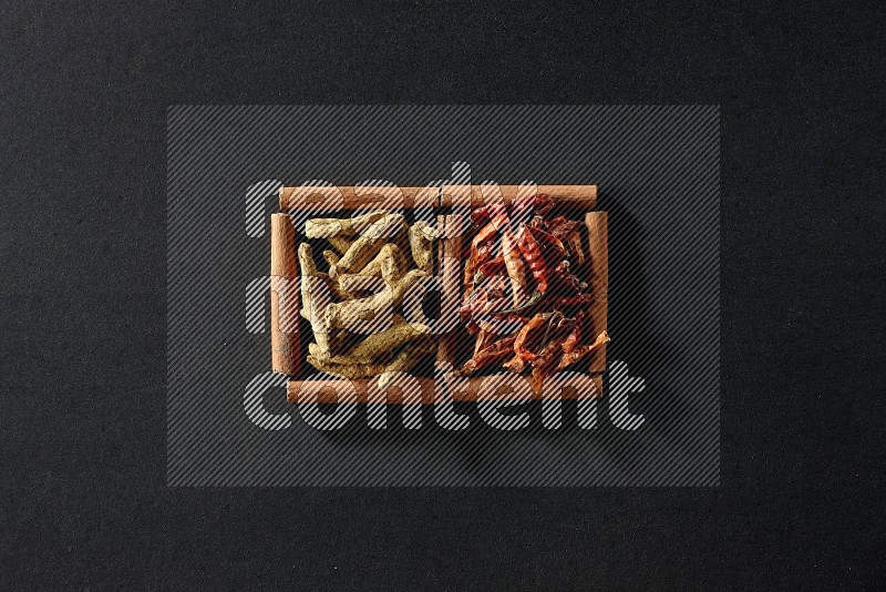 2 squares of cinnamon sticks full of chilis and turmeric fingers on black flooring