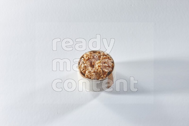 A beige ceramic bowl full of peeled walnuts on a white background in different angles