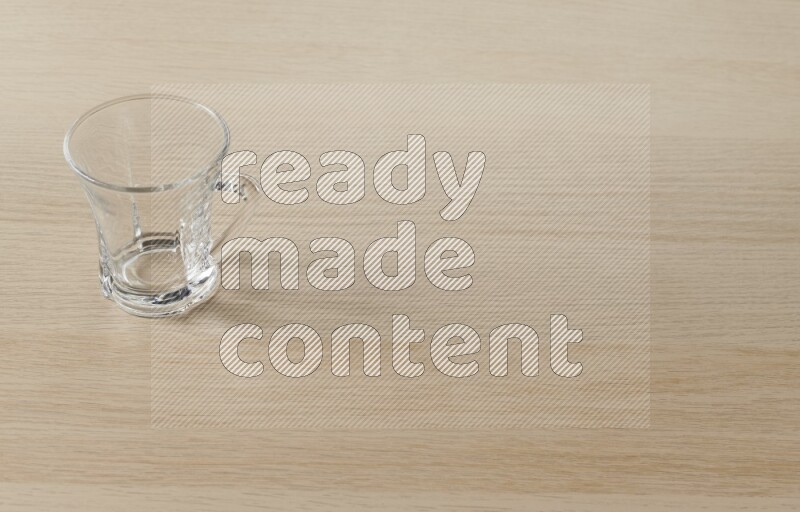 An empty glass cup on light wooden background