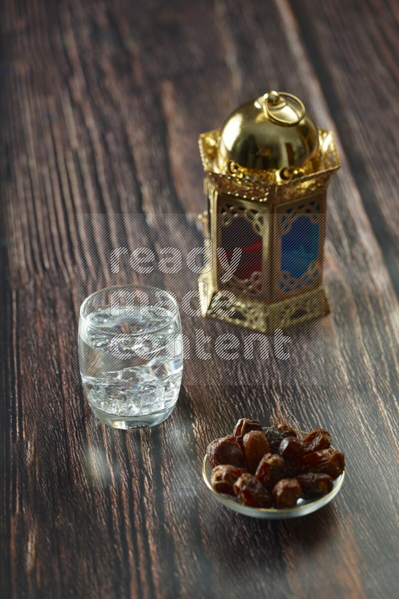 A golden lantern with different drinks, dates, nuts, prayer beads and quran on brown wooden background