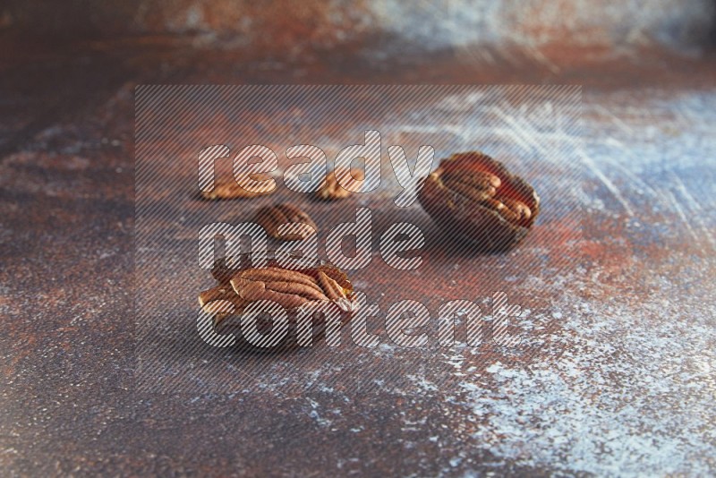 two pecan stuffed madjoul dates on a rustic reddish background
