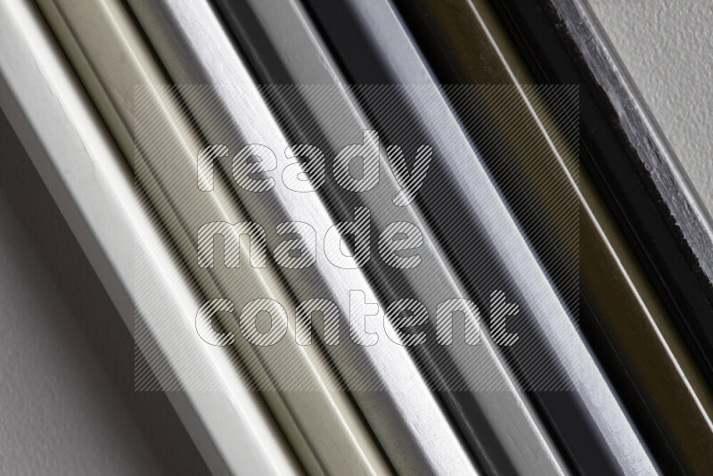 A collection of colored pencils arranged showcasing a gradient of white, grey and black hues on grey background