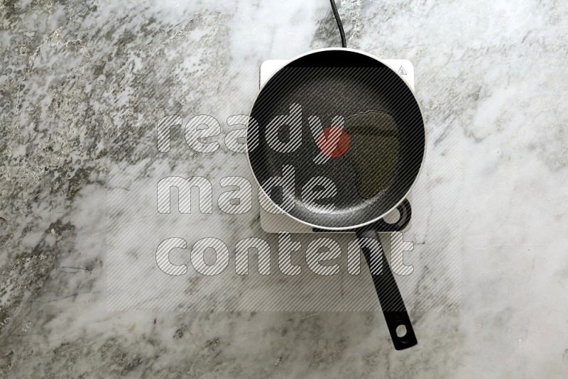 Frying pan on single electric stove on grey marble background