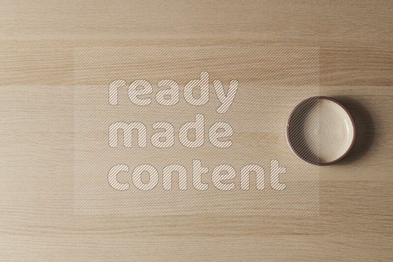 A beige pottery oven bowl on light wooden background