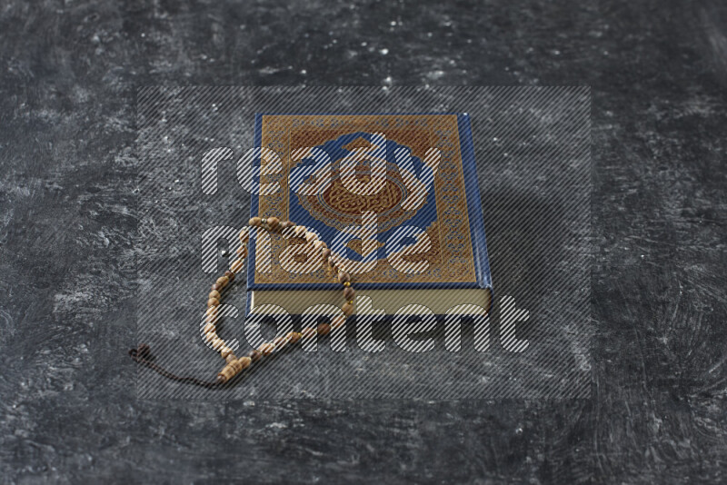 Quran with a prayer beads on textured black background