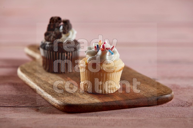 Vanilla mini cupcake topped with cream on a wooden board