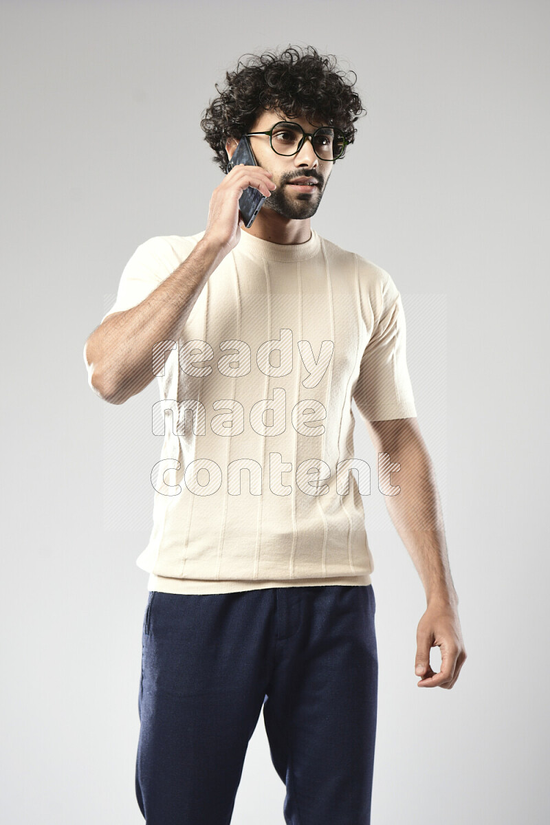 A man wearing casual standing and talking on the phone on white background