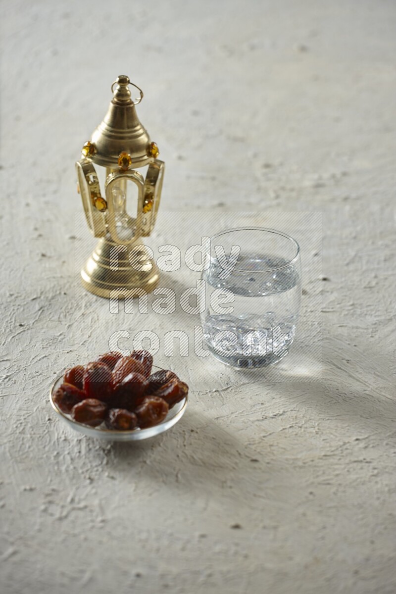A golden lantern with different drinks, dates, nuts, prayer beads and quran on textured white background