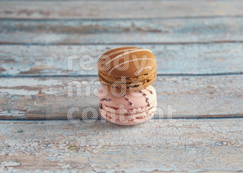 45º Shot of of two assorted Brown Irish Cream, and pink orange blossom  macarons on light blue background