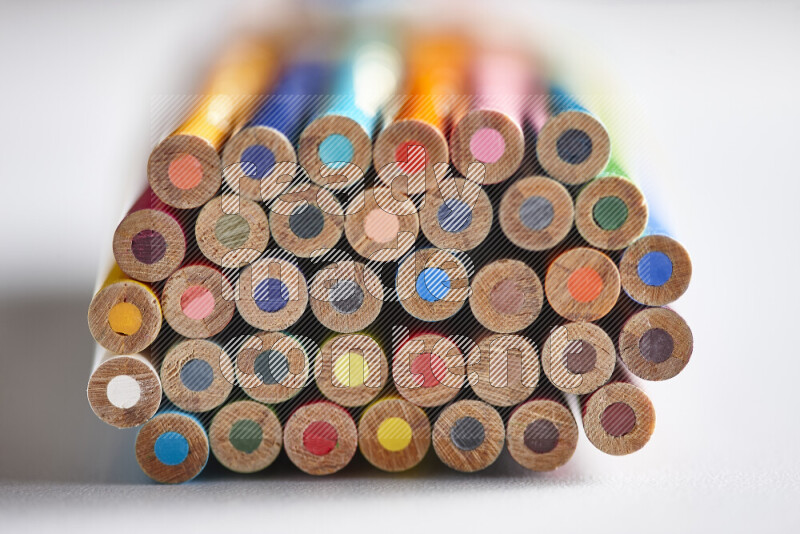 A close-up of the tips of colored pencils arranged in a bundle on white background