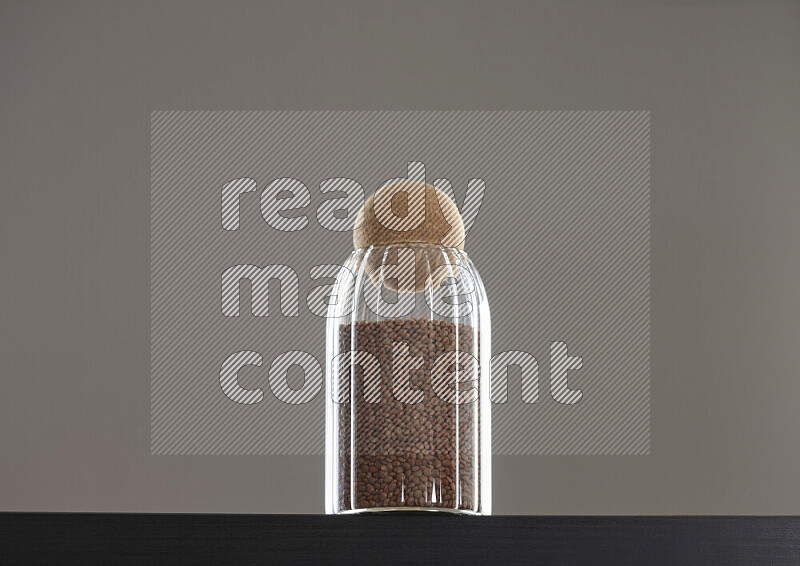 Brown lentils in a glass jar on black background