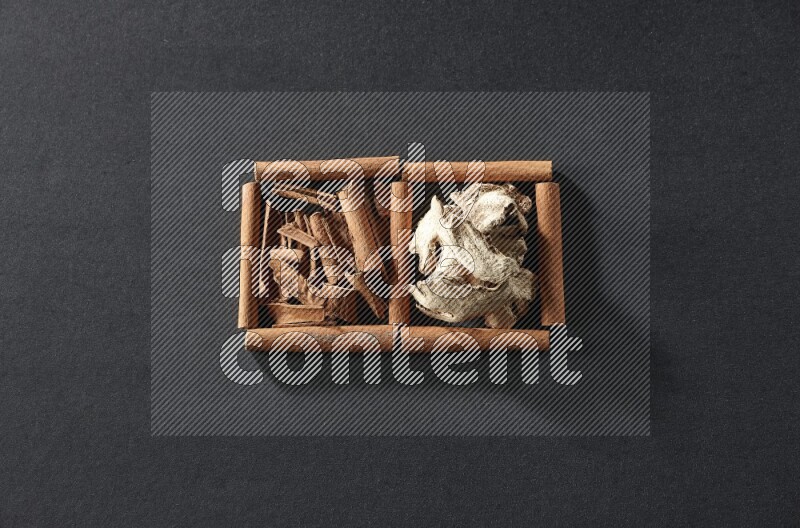 2 squares of cinnamon sticks full of cinnamon and ginger on black flooring