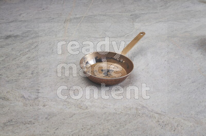 A small copper pan on grey marble background