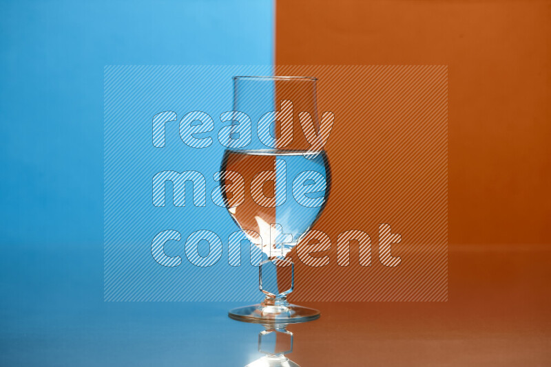 The image features a clear glassware filled with water, set against blue and dark orange background