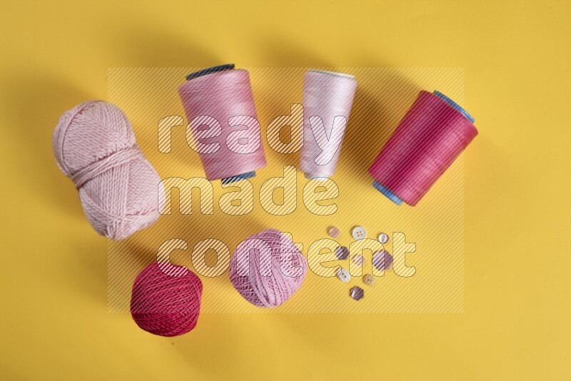 A pink collection of sewing and tailoring tools arranged on a yellow background