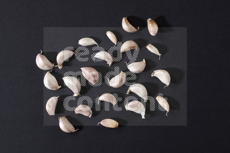 Garlic cloves on a black flooring in different angles