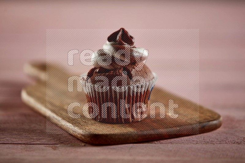 Chocolate cupcake topped with cream on a wooden board
