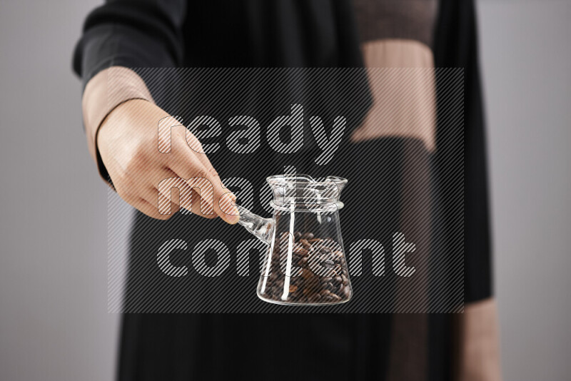 Woman in abaya holding different kinds of coffee beans in different positions