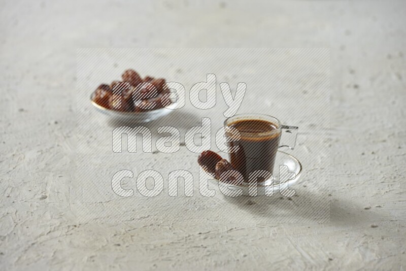 A coffee glass cup with dates and tea on textured white background