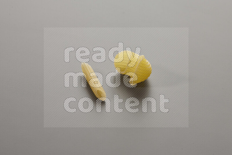 Mini penne pasta with other types of pasta on grey background