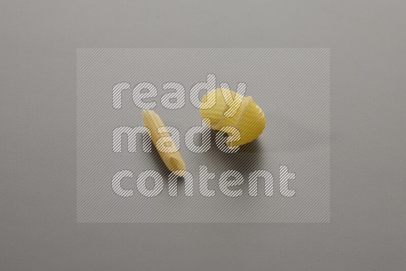Mini penne pasta with other types of pasta on grey background