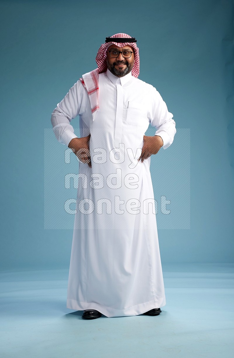 Saudi Man with shimag Standing Interacting with the camera on blue background