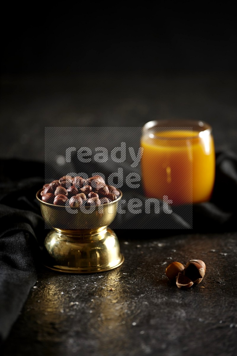 Nuts in a metal bowl with qamar eldin and a napkin in a dark setup