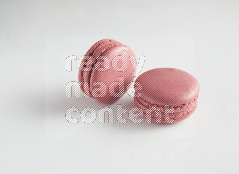 45º Shot of two Pink Raspberry macarons on white background