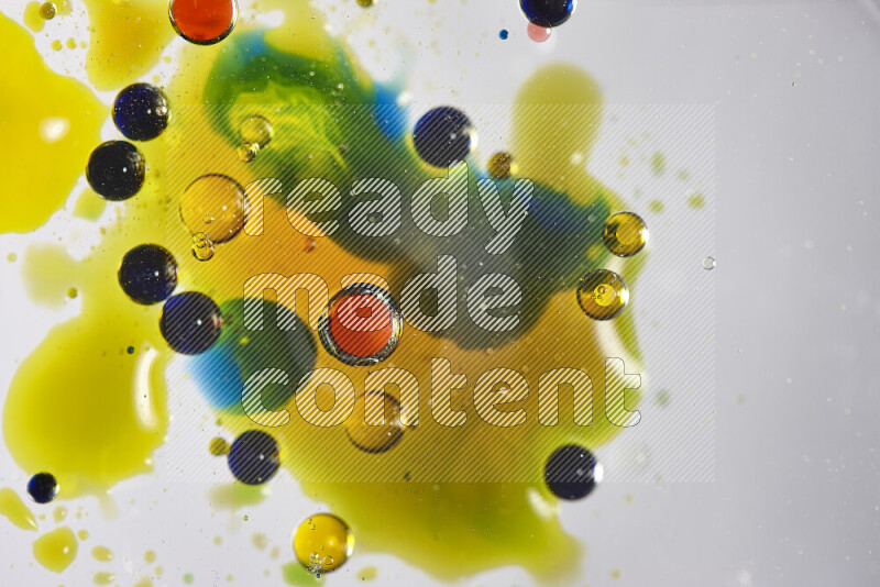 Close-ups of abstract red, blue, yellow and green watercolor drops on oil Surface on white background