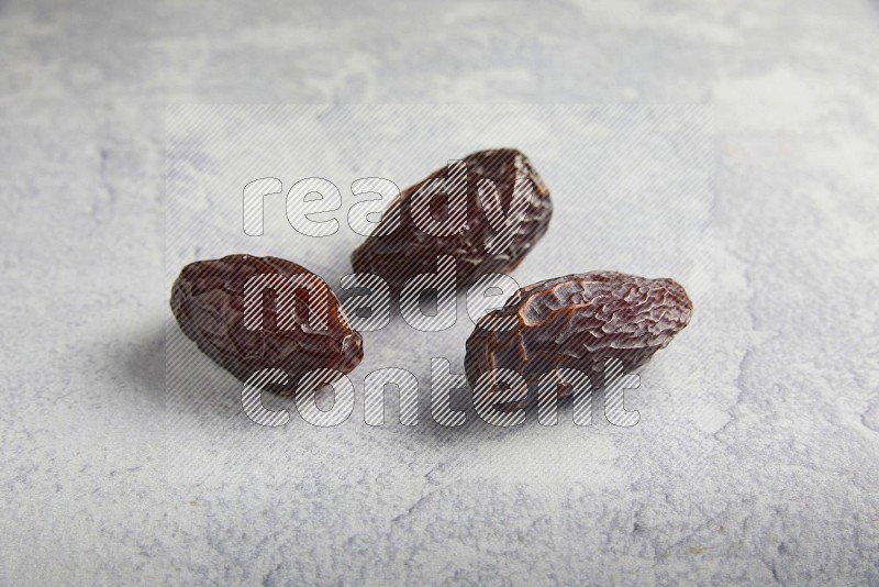 three madjoul dates on a light grey background