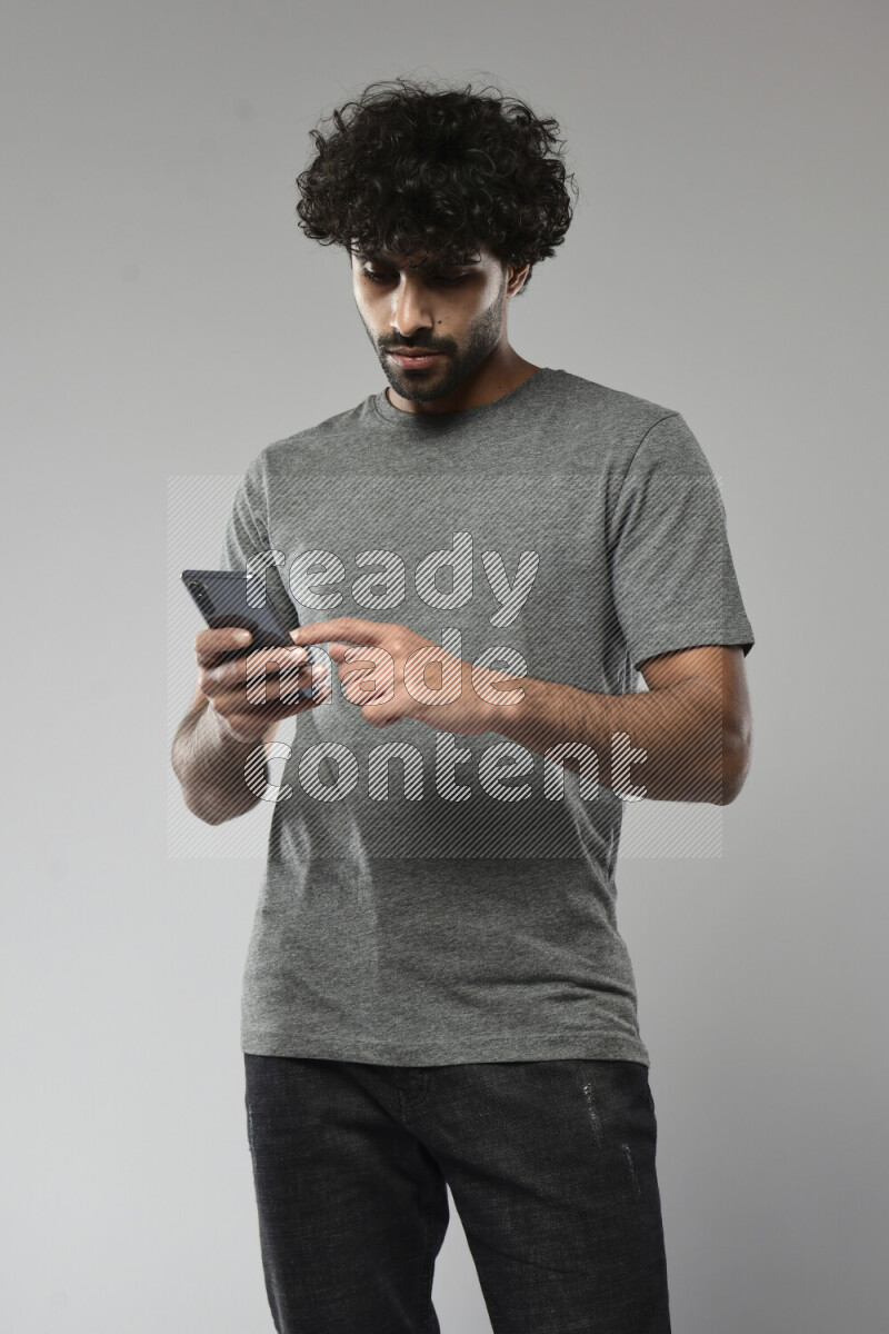 A man wearing casual standing and browsing on the phone on white background
