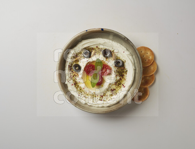 Lebnah garnished with cherry tomato, mint, olives & pine nuts in a grey pottery plate on a white background