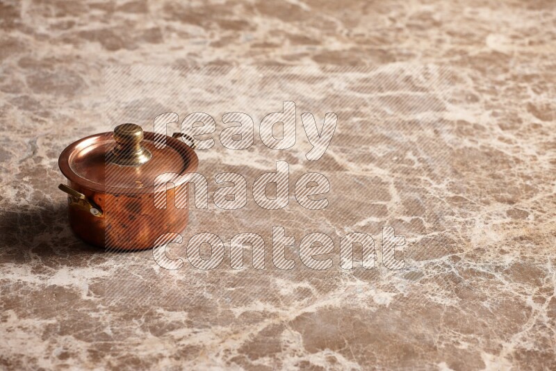 A small copper pot on beige marble background