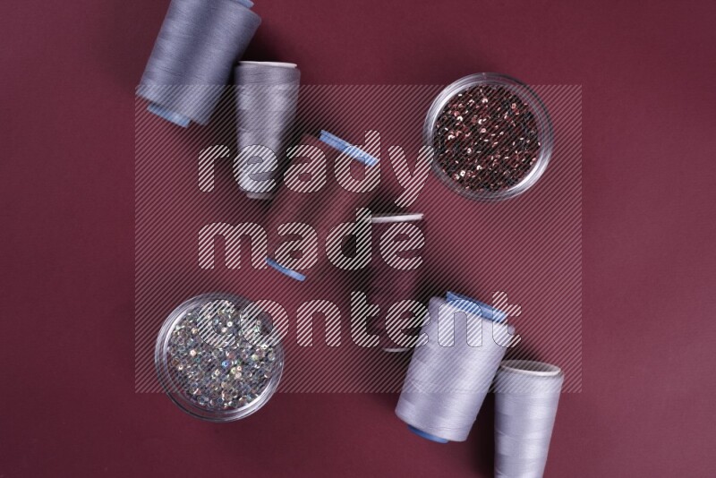 مجموعة من أدوات الخياطة والتفصيل رمادية اللون على خلفية حمراء