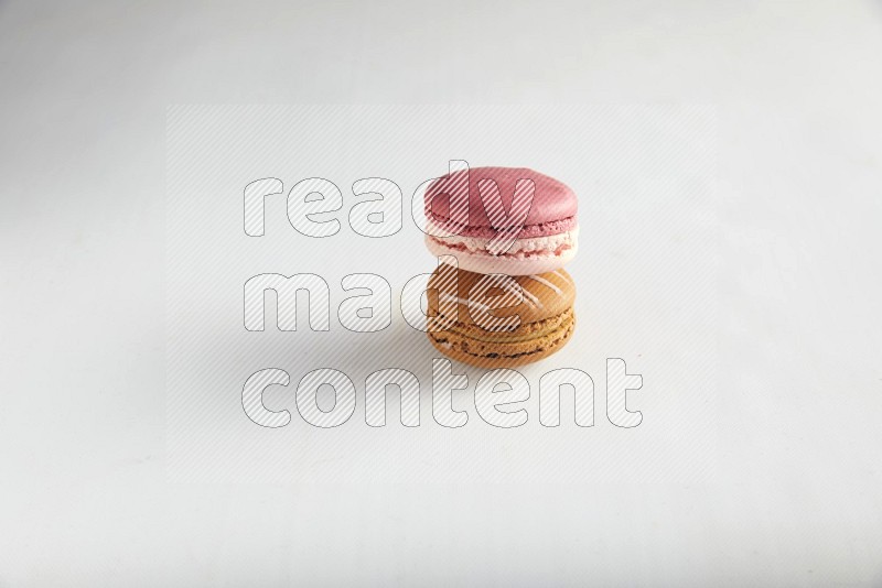 45º Shot of of two assorted Brown Irish Cream, and Pink Litchi Raspberry macarons on white background