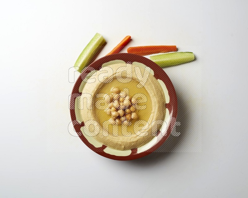 Hummus in a traditional plate garnished with roasted chickpeas  on a white background